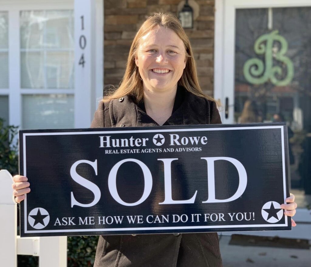 A satisfied Relevate client smiles while holding a "Sold" sign