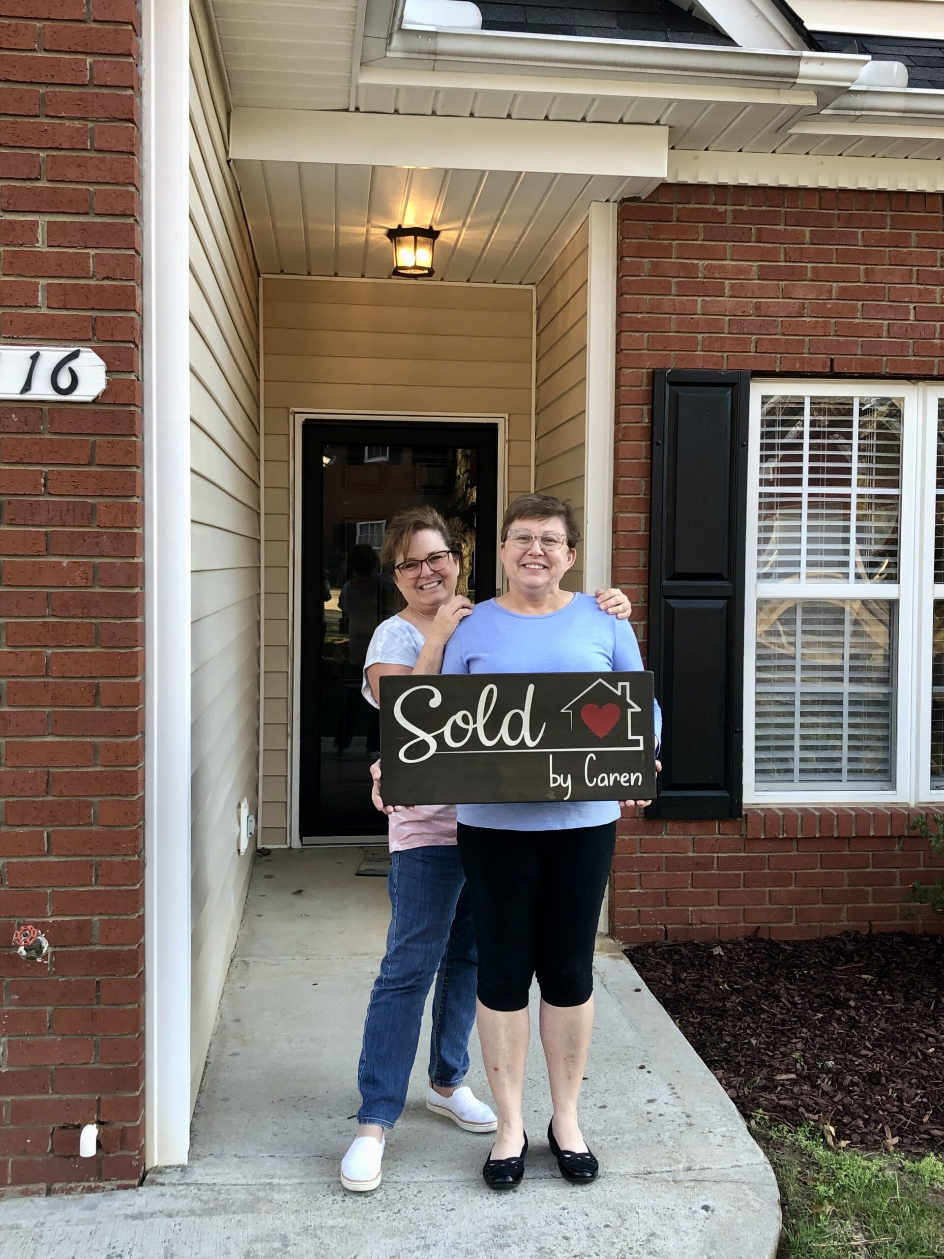 two satisfied homebuyers holding a sold sign