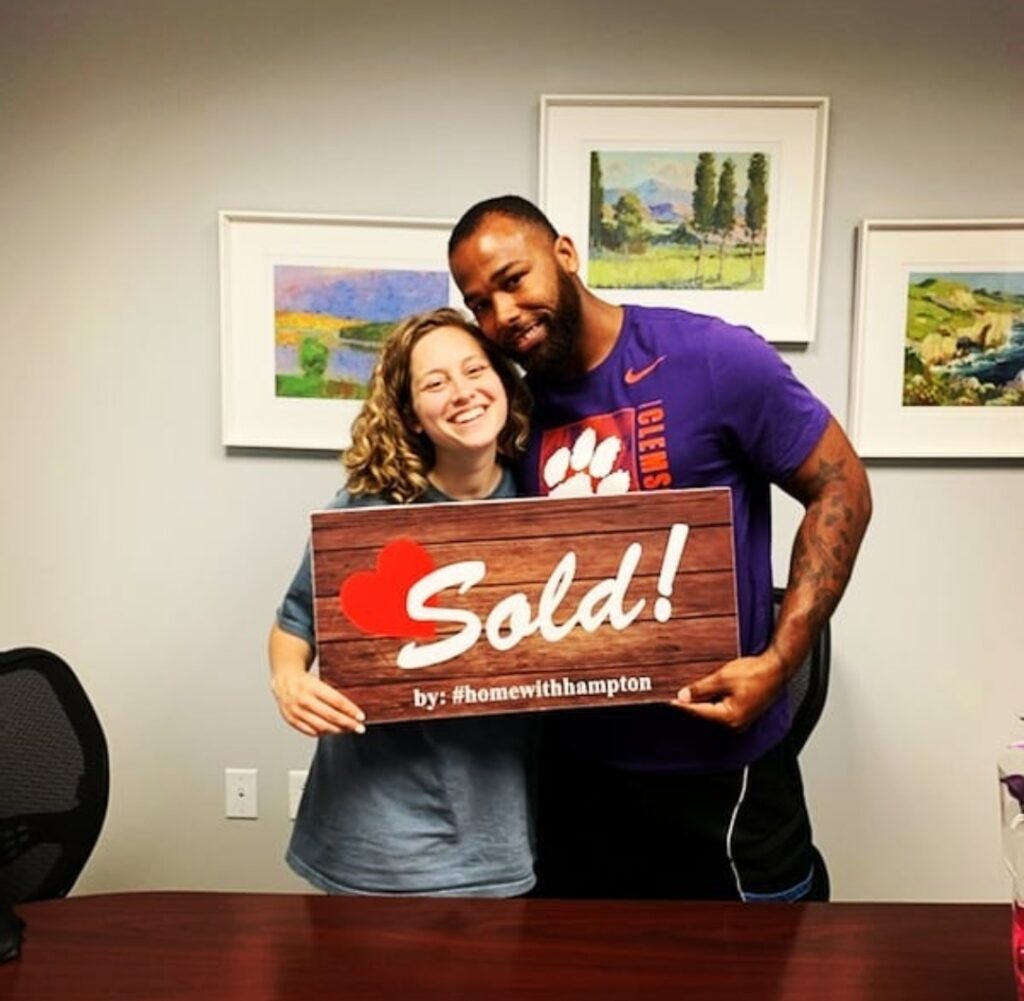 two satisfied homebuyers hold a SOLD sign