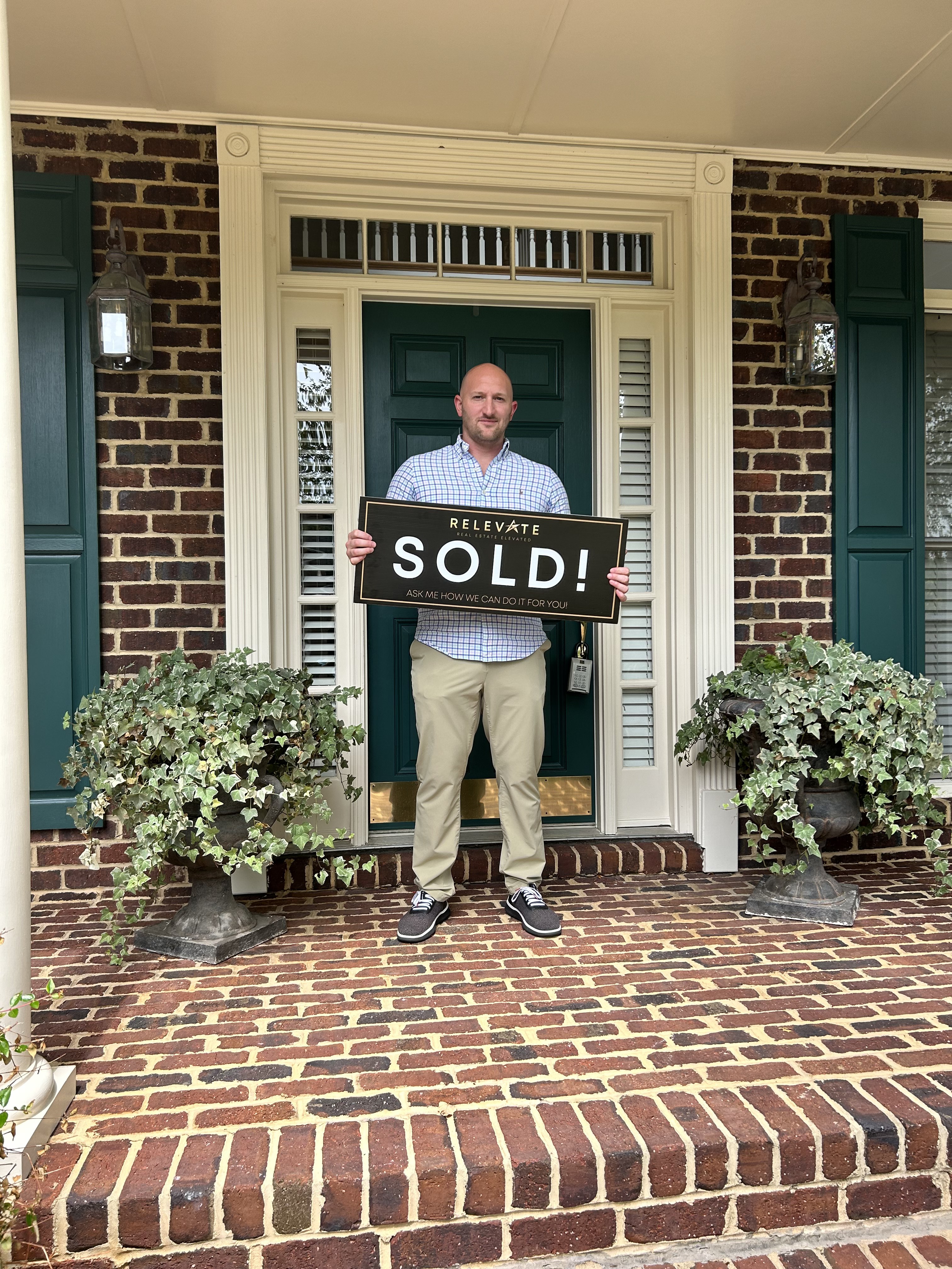 Young man holding a sold sign in front of his new house