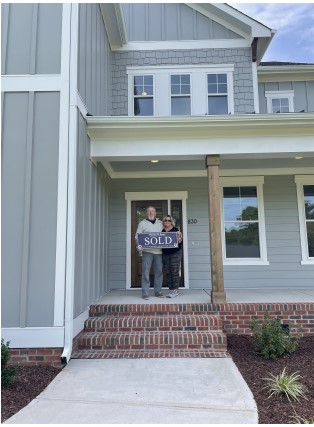 Picture of couple standing on porch they just bought the home to