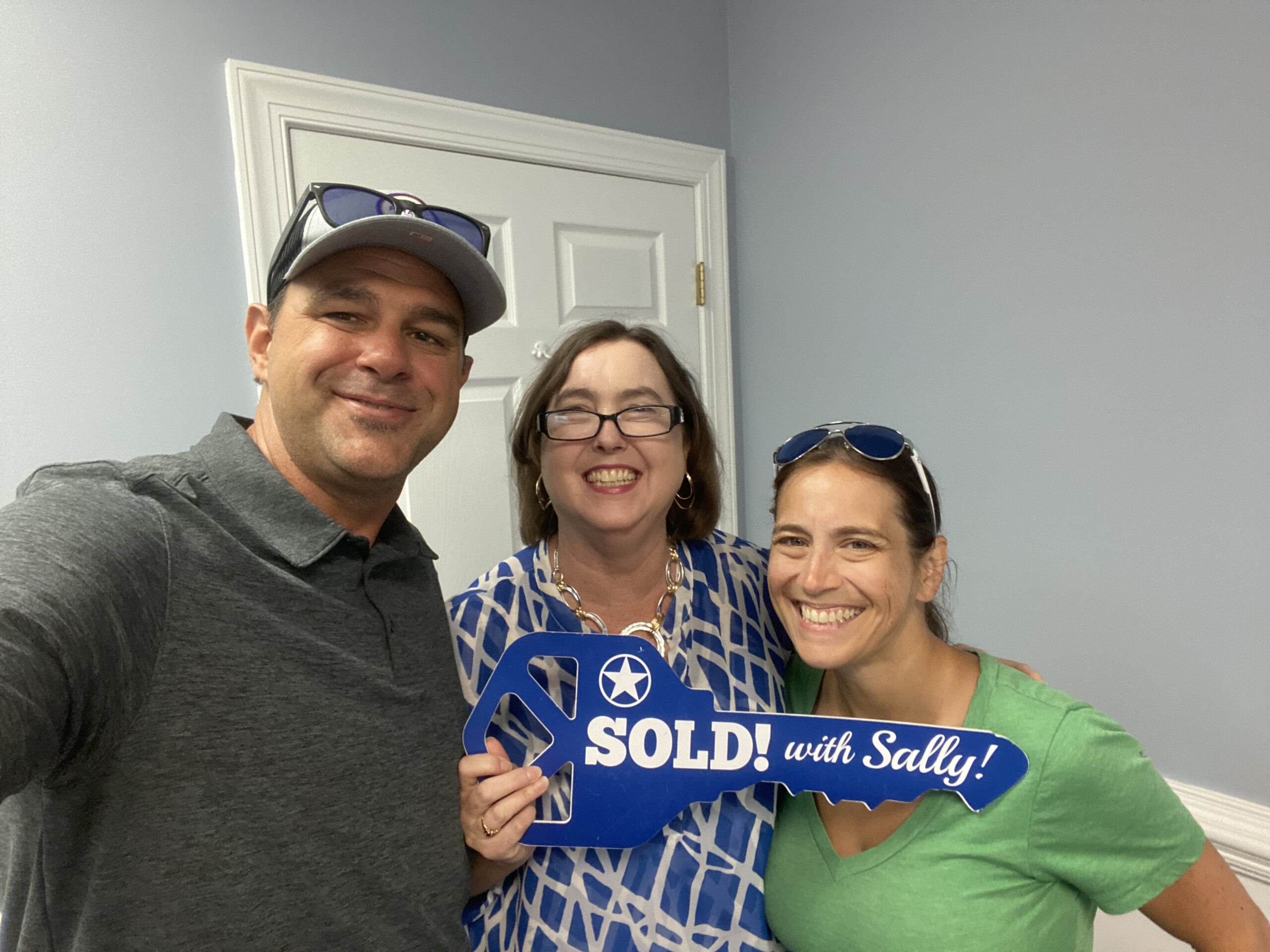 Happy couple standing with their agent holding a Sold Sign.