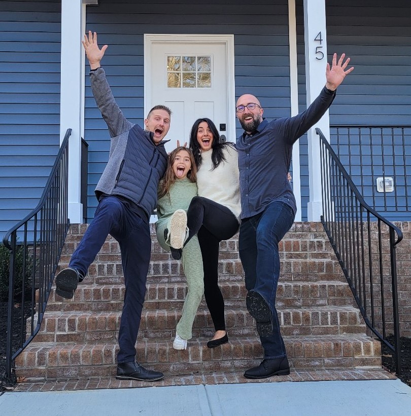 Happy family making a fun photo with their realtor in front of their new house